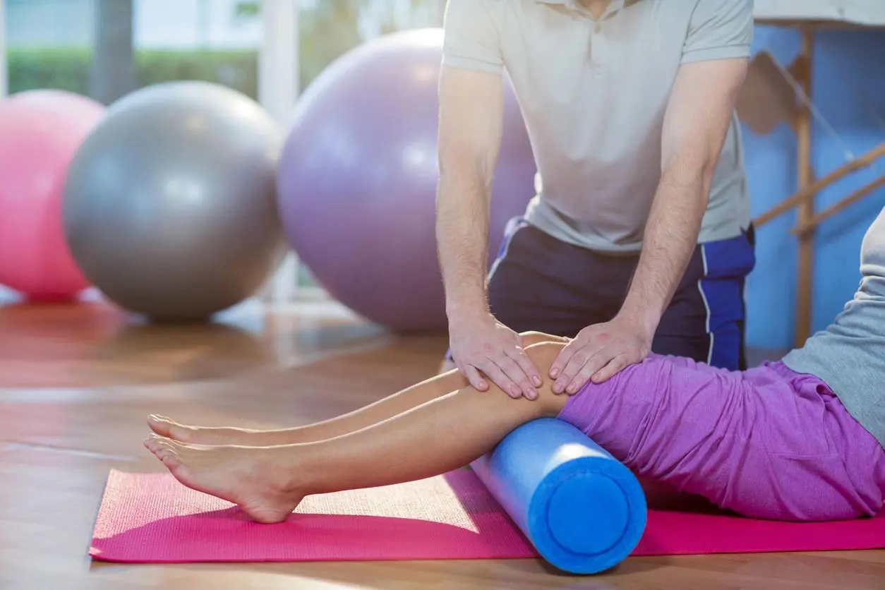 A person is rolling on the ground with a foam roller.