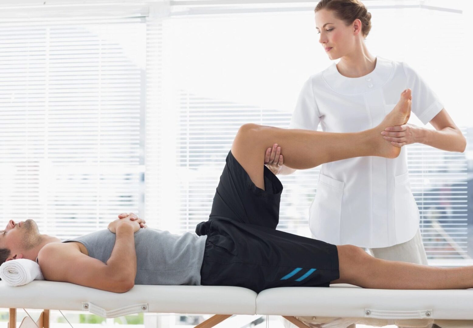 A person is stretching on the bed while another person watches.