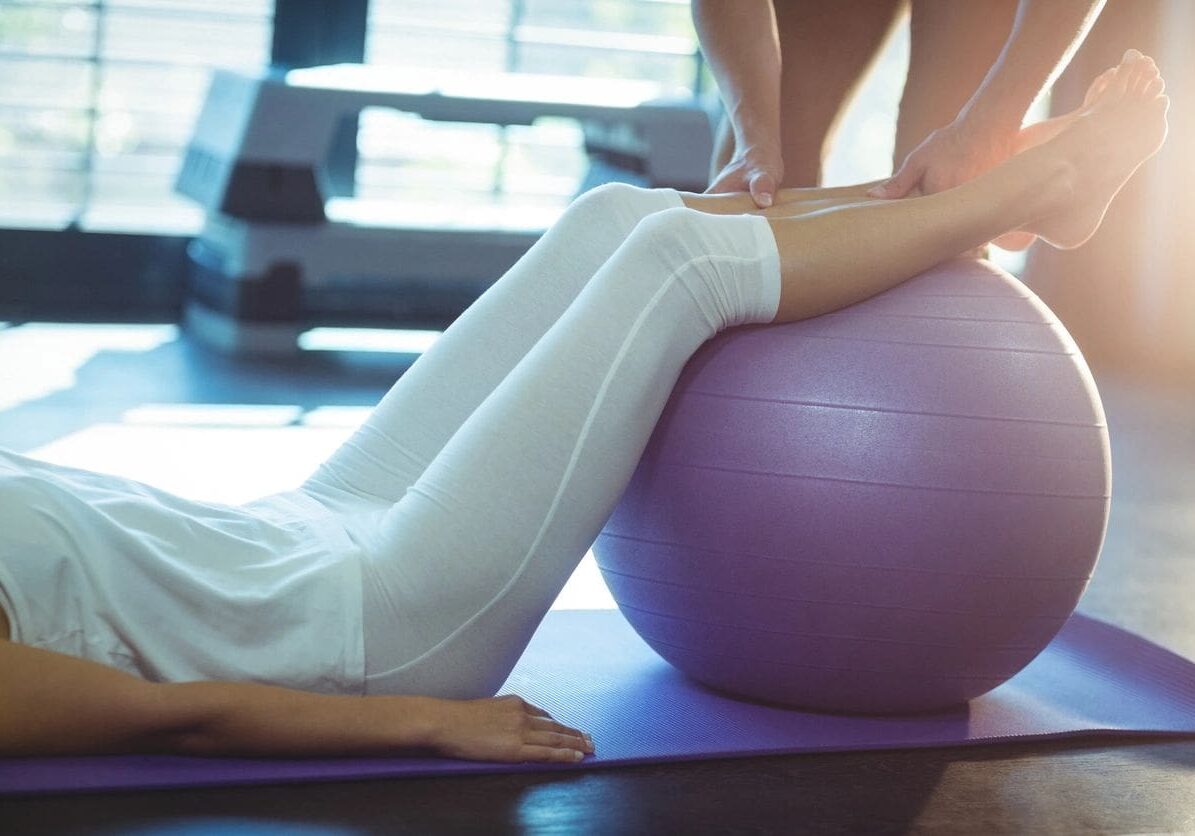 A person is sitting on the floor with their feet up on an exercise ball.